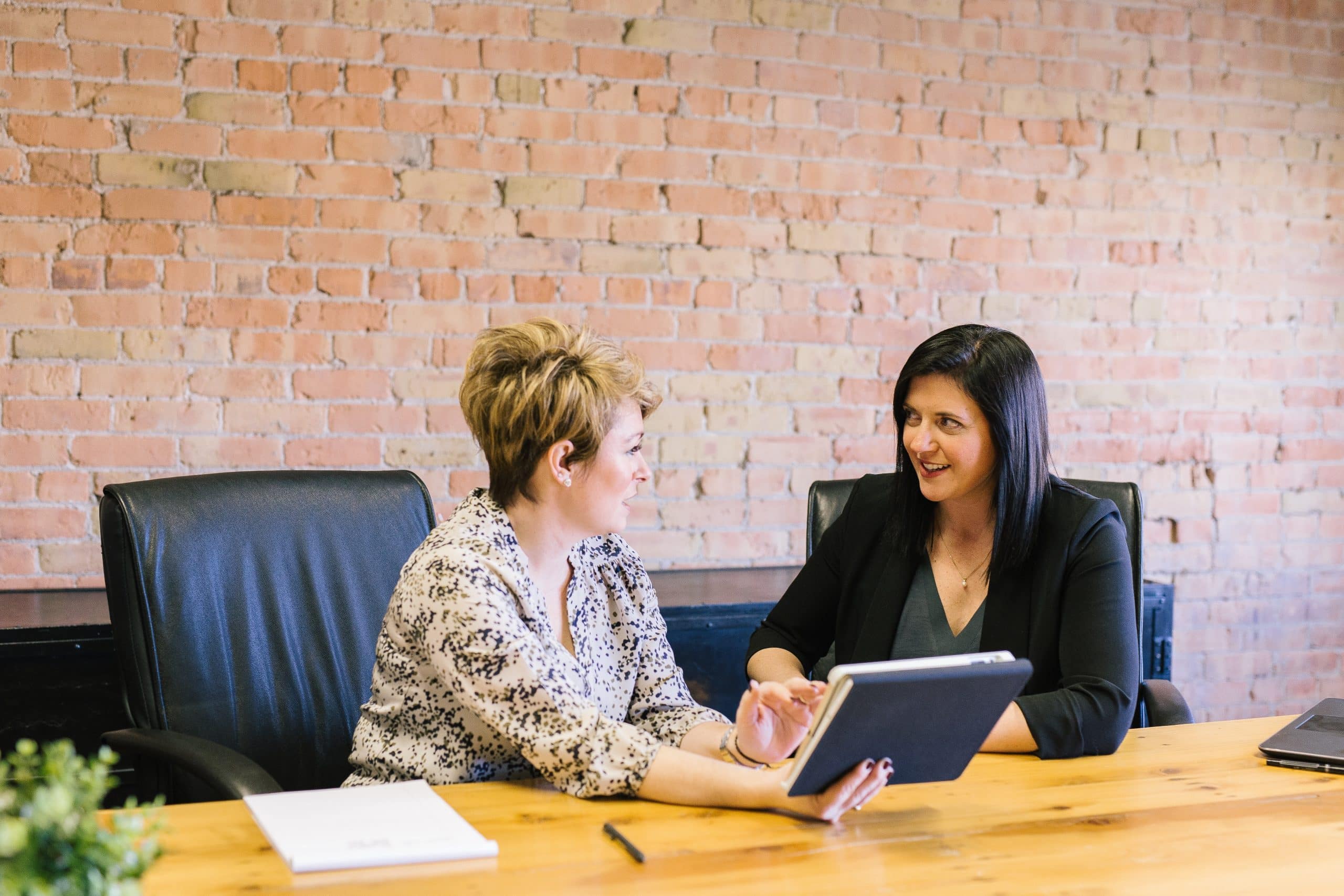 two women sitting at a desk having a conversation