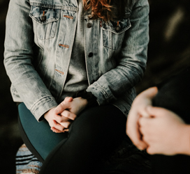 person sitting in a light denim jacket with hands in lap