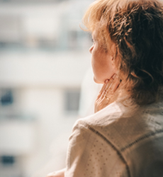 profile of a woman looking out of a city window holding her neck