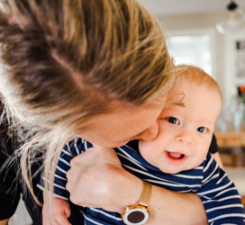mother hugging and kissing a smiling baby