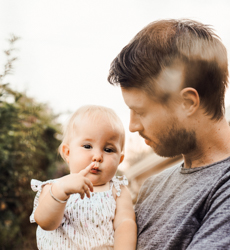 father holding young daughter outside