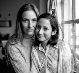 mother and daughter sitting by a window smiling