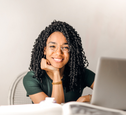 young woman smiling at a table behind a laptop