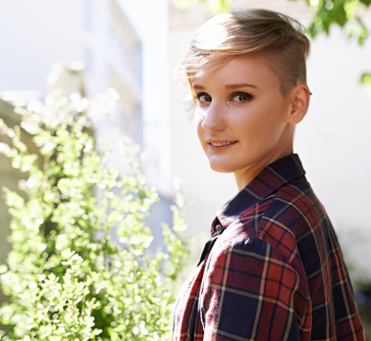 teenager with short hair smiling in a school garden